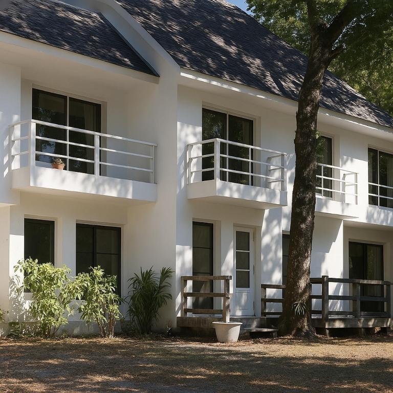 a white building with balconies and a tree at Oceanside Place Beach Resort in Ban Tha Fat