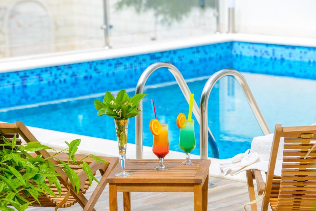 two glasses on a table next to a swimming pool at Tandem Apartments with Swimming pool in Cavtat