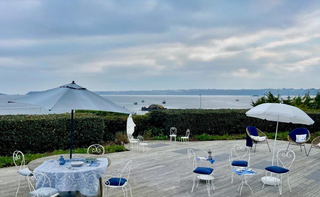 un patio con tavoli, sedie e un ombrellone di Ty Mamm Doué a Ploubazlanec