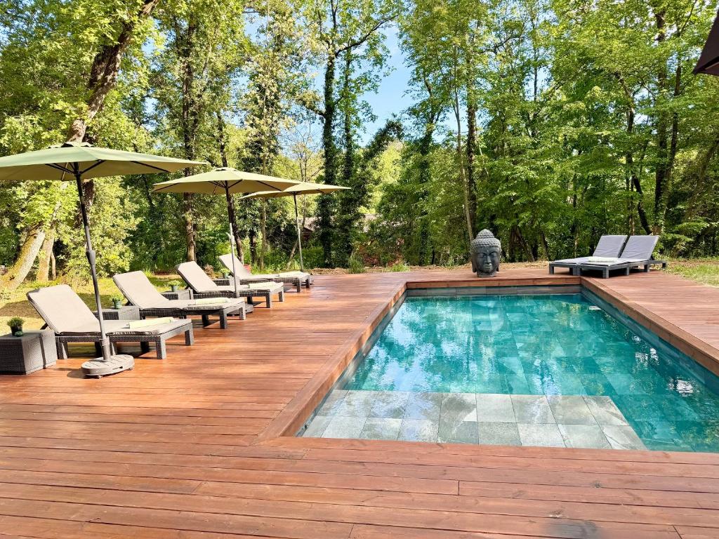- une piscine avec des chaises et des parasols sur une terrasse en bois dans l'établissement Villa with pool, petanque, large green space, à Roquefort-les-Pins