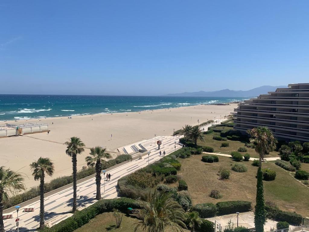 - une vue sur une plage bordée de palmiers et un bâtiment dans l'établissement T2 les pieds dans le sable !, à Canet