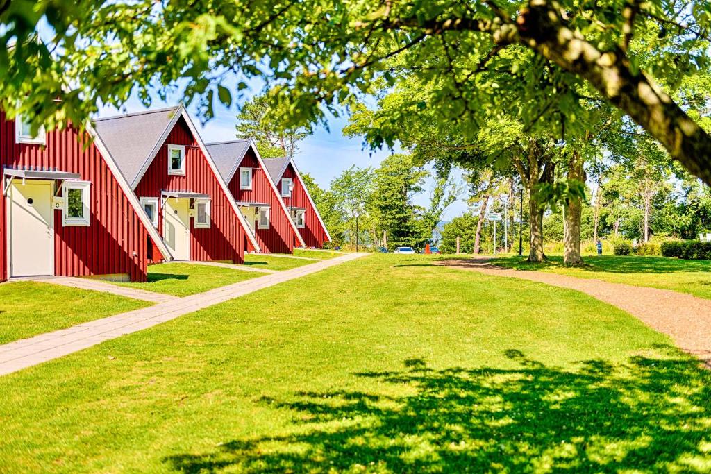a row of red barns on a grass field at Mötesplats Borstahusen in Landskrona