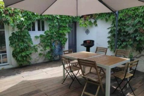 une table et des chaises avec un parasol sur une terrasse dans l'établissement Maison Vacances La Rochelle, à La Rochelle