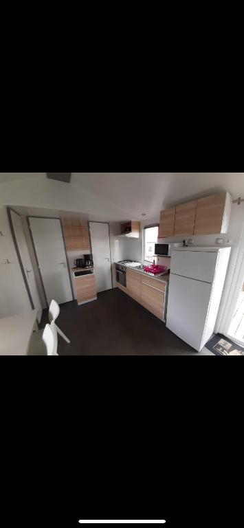 Elle comprend une petite cuisine avec des placards blancs et une fenêtre. dans l'établissement Mobilhome, à Litteau