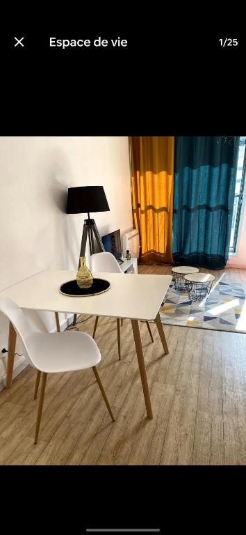 une table blanche avec une lampe et deux chaises blanches dans l'établissement La grosse horloge, à La Rochelle