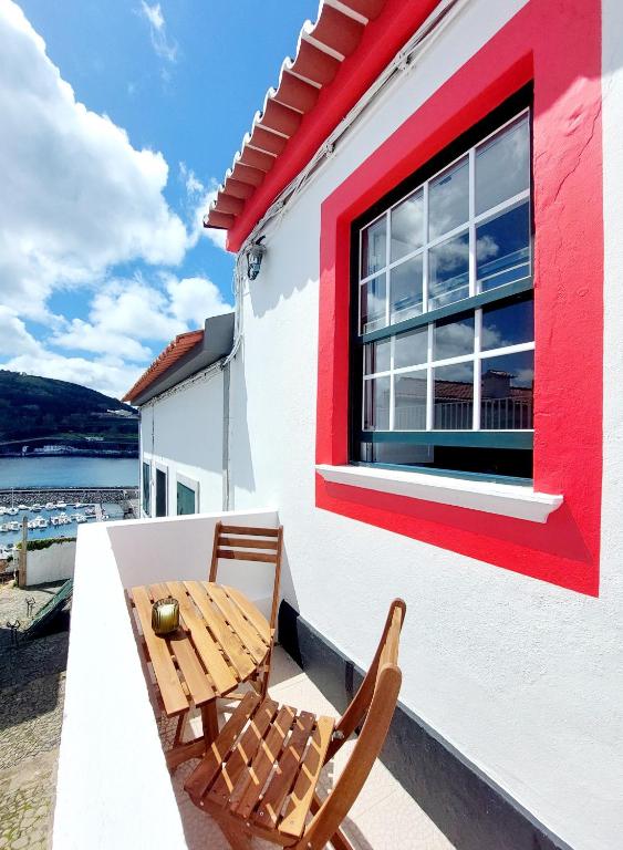 a patio with two chairs and a table and a window at Casa do Beco in Angra do Heroísmo
