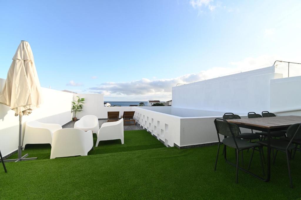 eine Terrasse mit weißen Möbeln und grünem Gras in der Unterkunft Lagoa Sea View by Vacationy in Lagoa