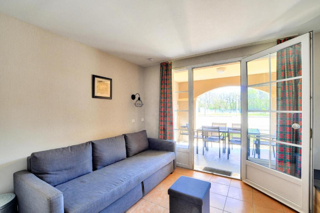 un salon avec un canapé bleu et un balcon dans l'établissement La résidence du Lac - maeva Home - Appartement 2 pièces 4 personnes - Sélection MAE-5611, à Monflanquin