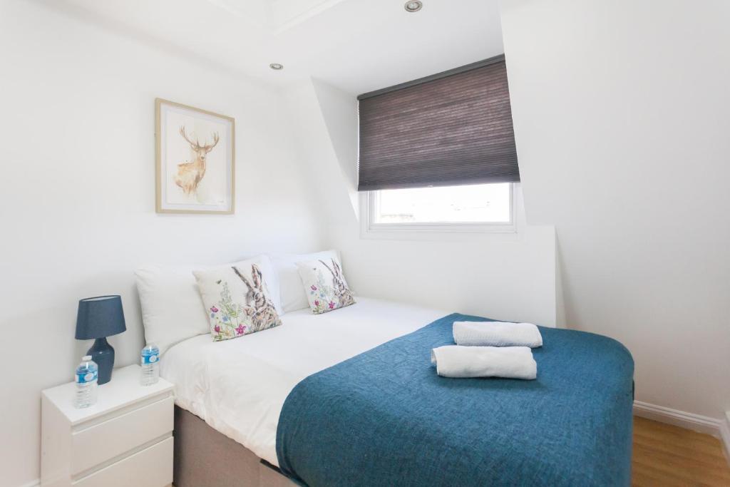 Un dormitorio con una cama con una manta azul. en Euston Modern Apartments, en Londres
