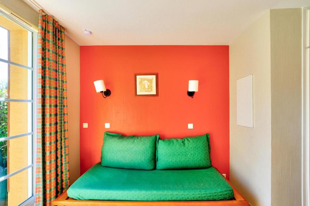 - un lit vert dans une chambre avec un mur orange dans l'établissement La résidence du Lac - maeva Home - Appartement 3 pièces 6 personnes - Sélection MAE-0401, à Monflanquin