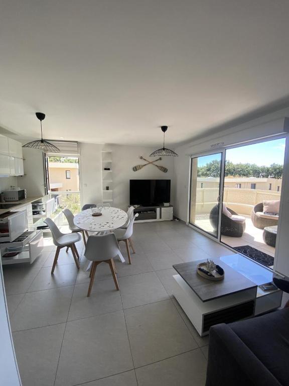 un salon avec une table et des chaises et une cuisine dans l'établissement Allée des Oliviers - maeva Home - Appartement 3 pièces 6 personnes - Prestige MAE-5001, à Saint-Elme