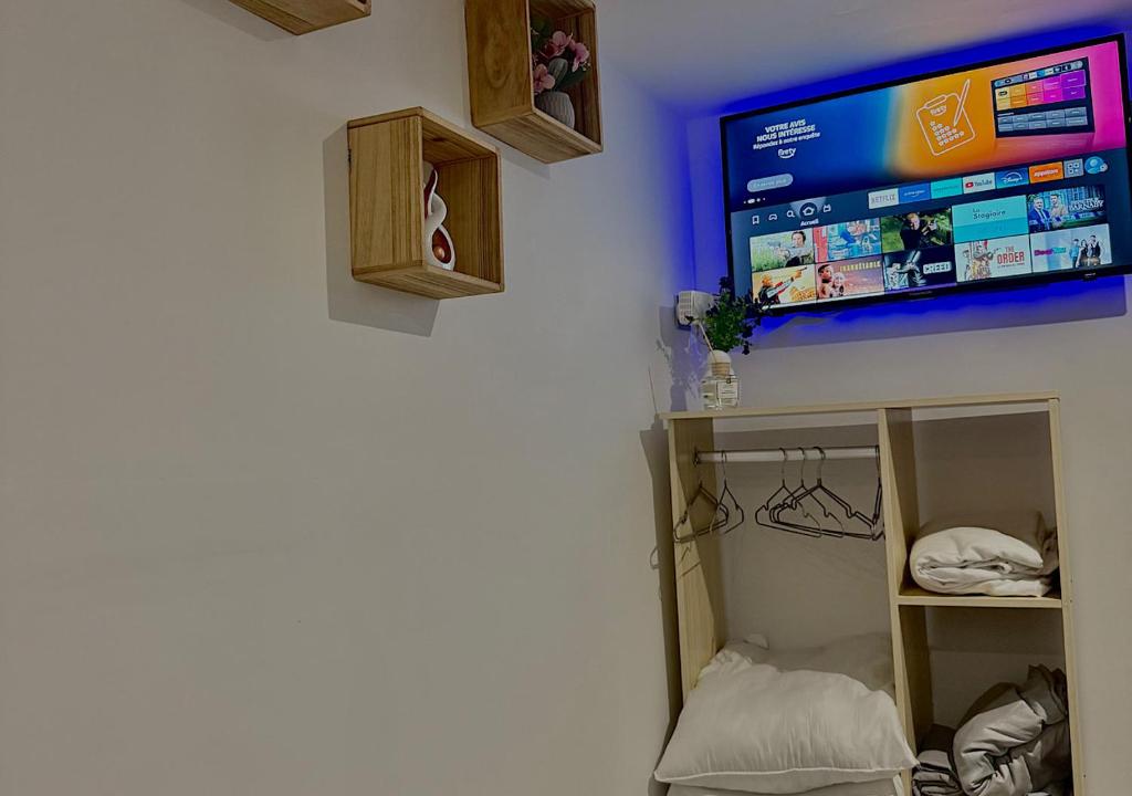 une pièce avec une télévision à écran plat sur un mur dans l'établissement Dépendance cosy près de Paris, à Vernouillet