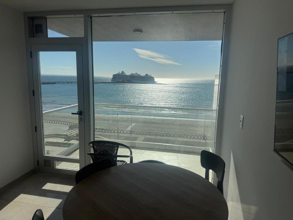 a table and chairs in a room with a view of the ocean at Crystal al mar in Puerto Madryn