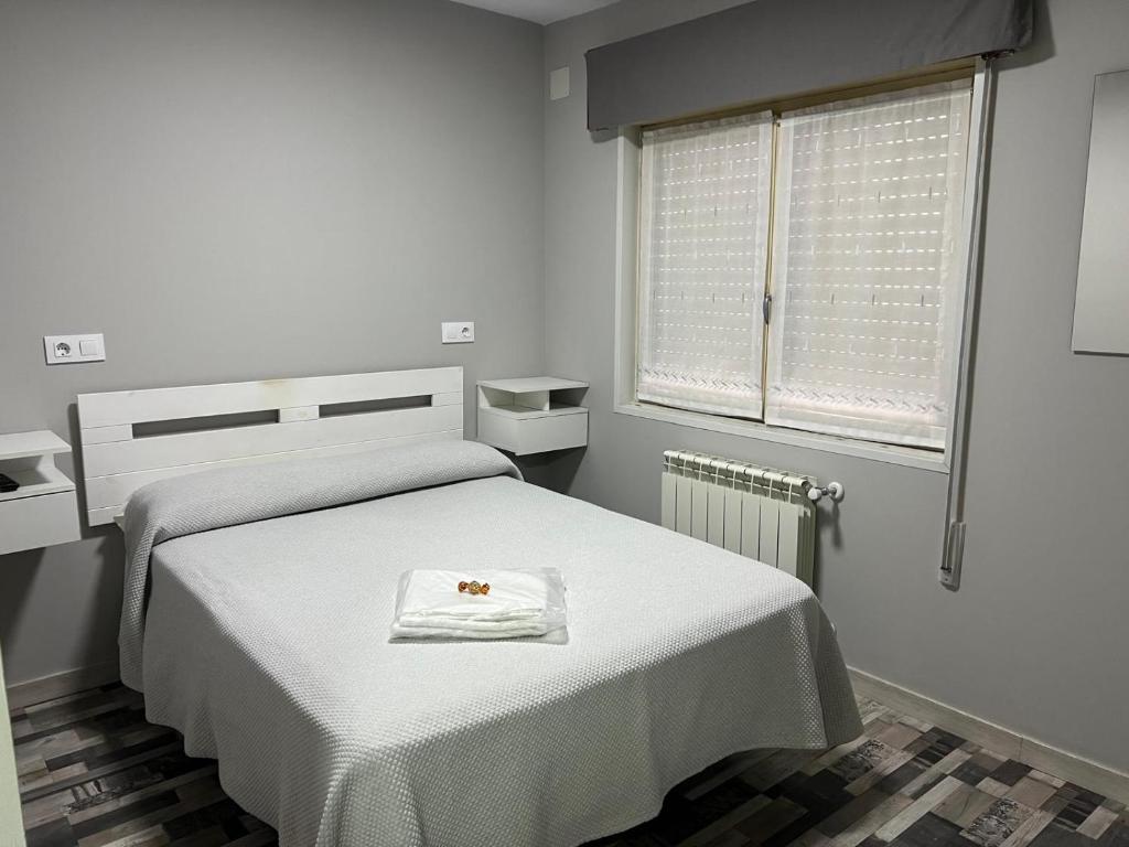 Habitación blanca con cama y toalla en Coalla Rooms Luxe, en Lugones