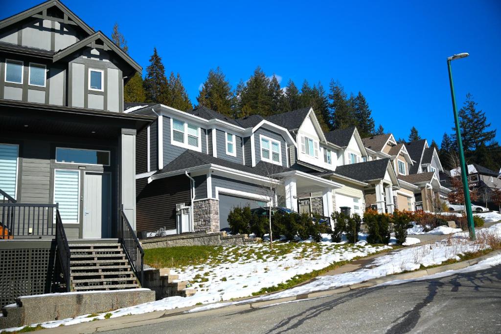 a row of houses on a snow covered street at Modern Zen House, EV Plugin, Mountains, Trails & Stylish Urban Vibe in Coquitlam