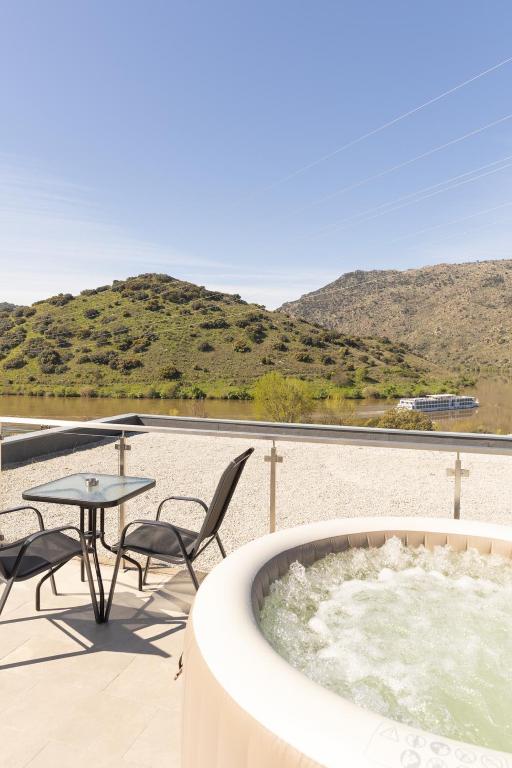 a hot tub on a patio with a table and chairs at Douro Elegance Suites in Torre de Moncorvo