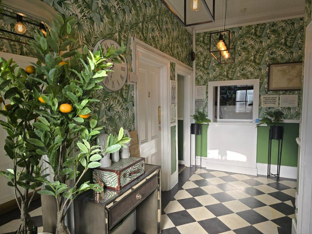 a hallway with green and white patterned walls and a plant at Avis Hotel in Bromley