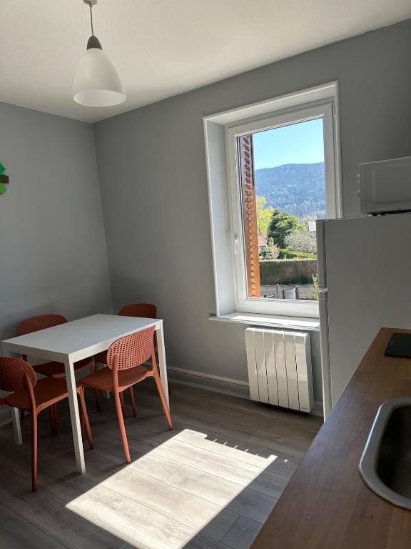 une cuisine avec une table et des chaises et une fenêtre dans l'établissement Appartement cosy avec vue sur les montagnes, à Saint-Nabord