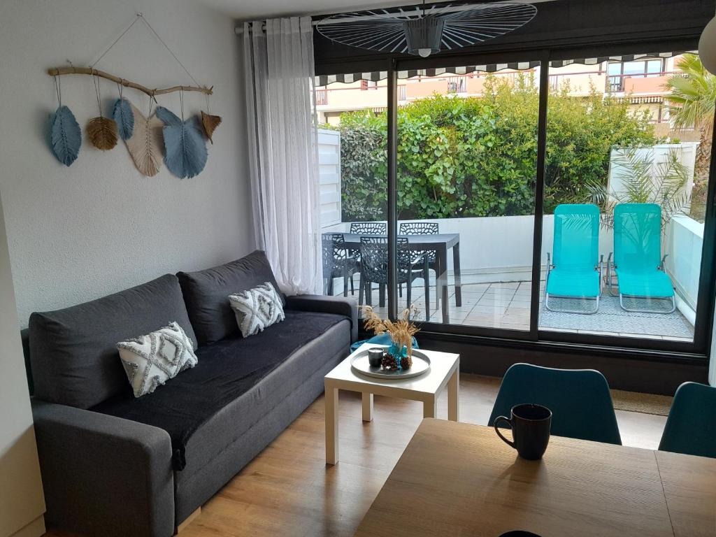 a living room with a couch and a table at Bleu Océan - Sur le port Appartement avec piscine, terrasse, parking in Capbreton