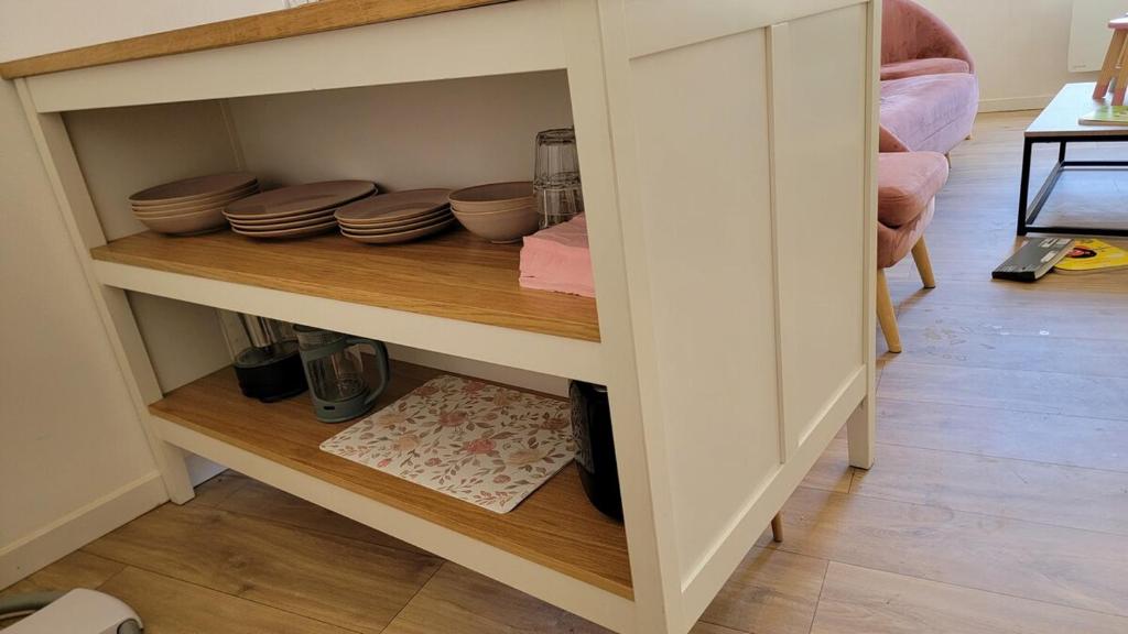 une armoire avec des assiettes et des bols sur une étagère dans l'établissement T1 bis plein pied, à Saumur