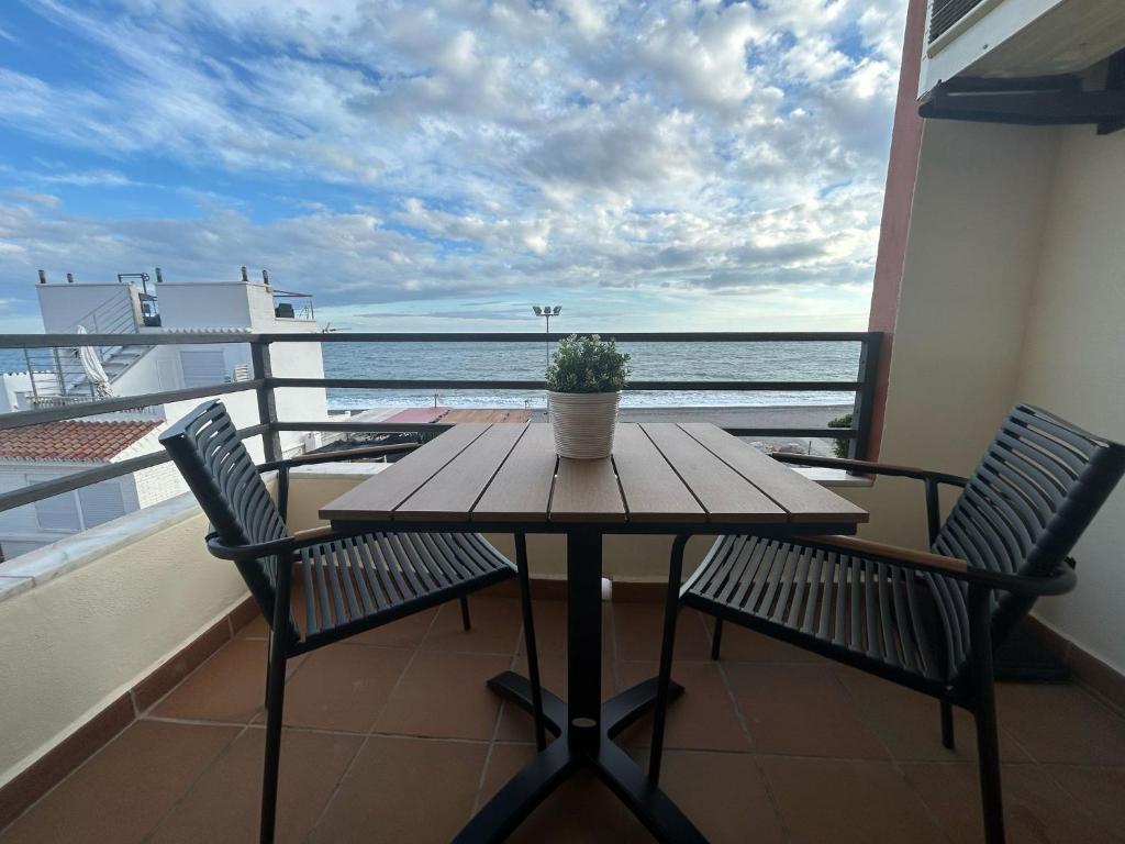 ein Tisch und Stühle auf einem Balkon mit Blick auf das Meer in der Unterkunft Moderno Apartamento en primera linea de playa con terraza y vistas al mar- Caleta del Puerto in Caleta De Velez