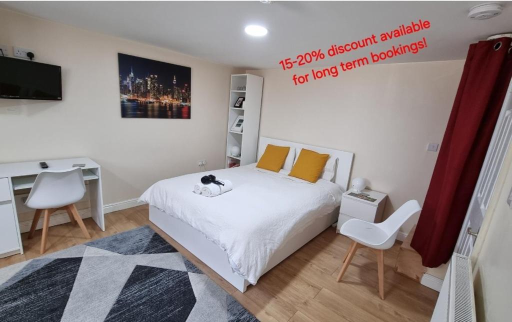 a bedroom with a white bed and a desk and a computer at Lovely studio-flat with free parking, free WiFi. in Leeds