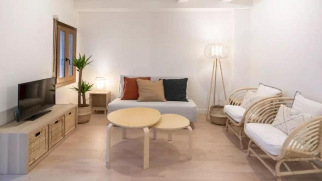 a living room with a couch and a table and a tv at Apartamento Balears Navarra Ibiza in Ibiza Town