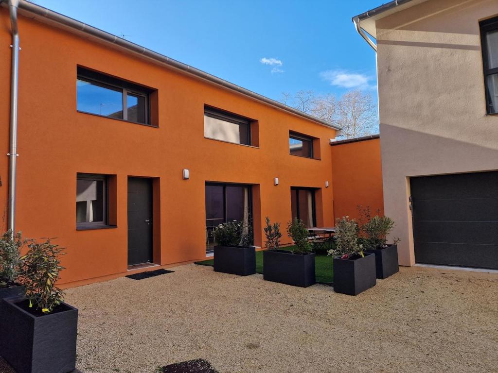 an orange house with plants in front of it at Maison neuve clim terrasse TV wifi fibré parking in Oullins
