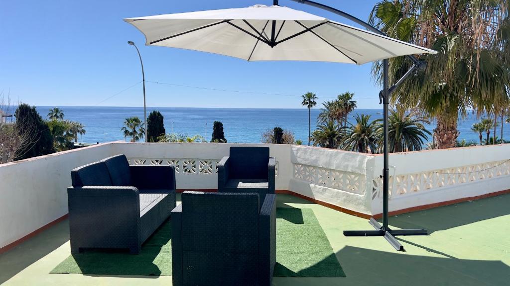 eine Terrasse mit einem Sonnenschirm, Stühlen und Meerblick in der Unterkunft Villa Torrecilla Sea View - South Costa, Nerja in Nerja