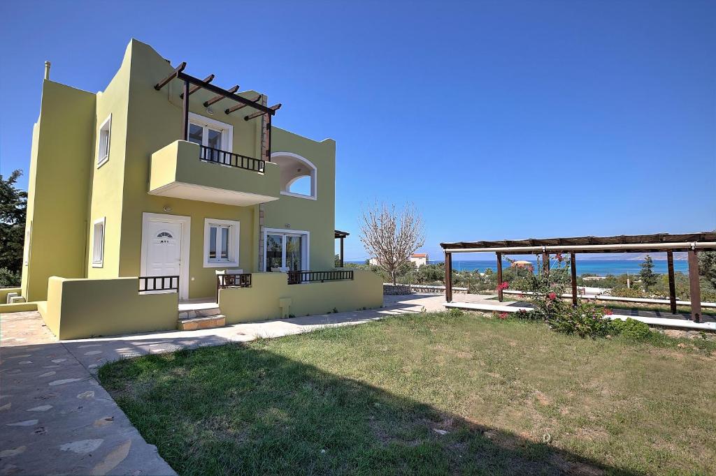 a large yellow house with a yard in front of it at Psaromatis in Elafonisos