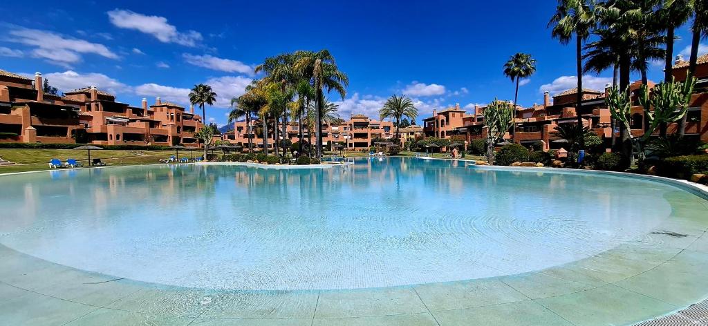 duży basen w ośrodku z palmami w obiekcie Alhambra del Golf - Guadalmina w mieście Estepona