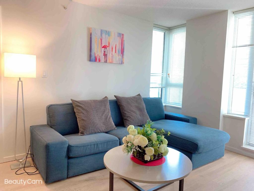 ein Wohnzimmer mit einem blauen Sofa und einem Tisch in der Unterkunft Cozy Perfect &elegant 2bed 1 bath in Richmond center in Richmond