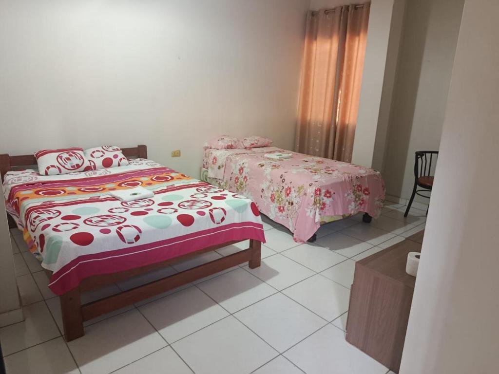 a bedroom with two beds and a table at Hospedaje Cielo Marino in Zorritos