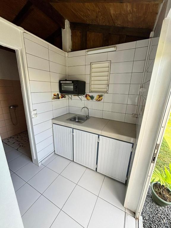 a small kitchen with a sink and a microwave at Maisonnette de campagne, Sofaia à 5 min in Sainte-Rose