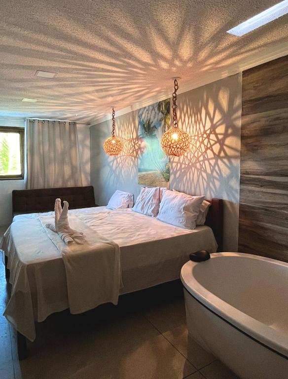 a bedroom with a bed and a bath tub at Suítes Ventos e Velas Praia in Pôrto de Pedras