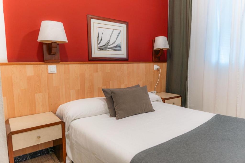 a bedroom with two beds and a red wall at Hostal Regina in Blanes