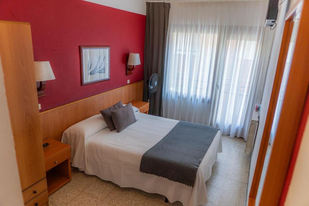 a hotel room with a bed and a red wall at Hostal Regina in Blanes