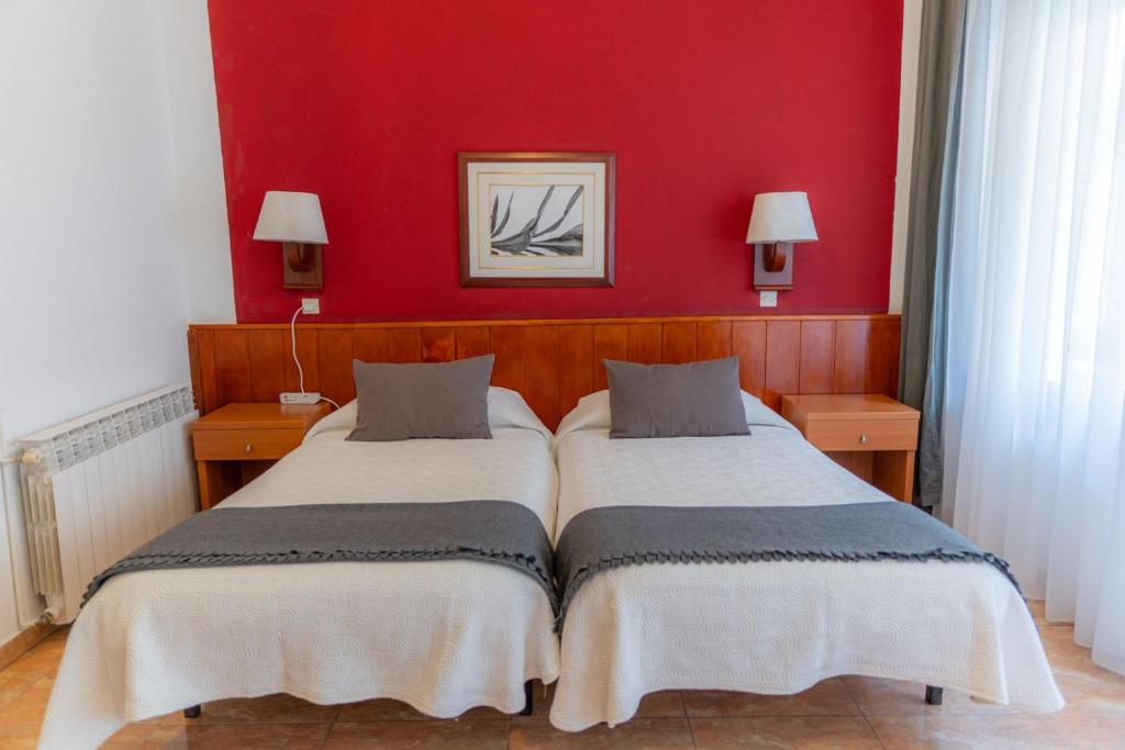 a bedroom with two beds and a red wall at Hostal Regina in Blanes