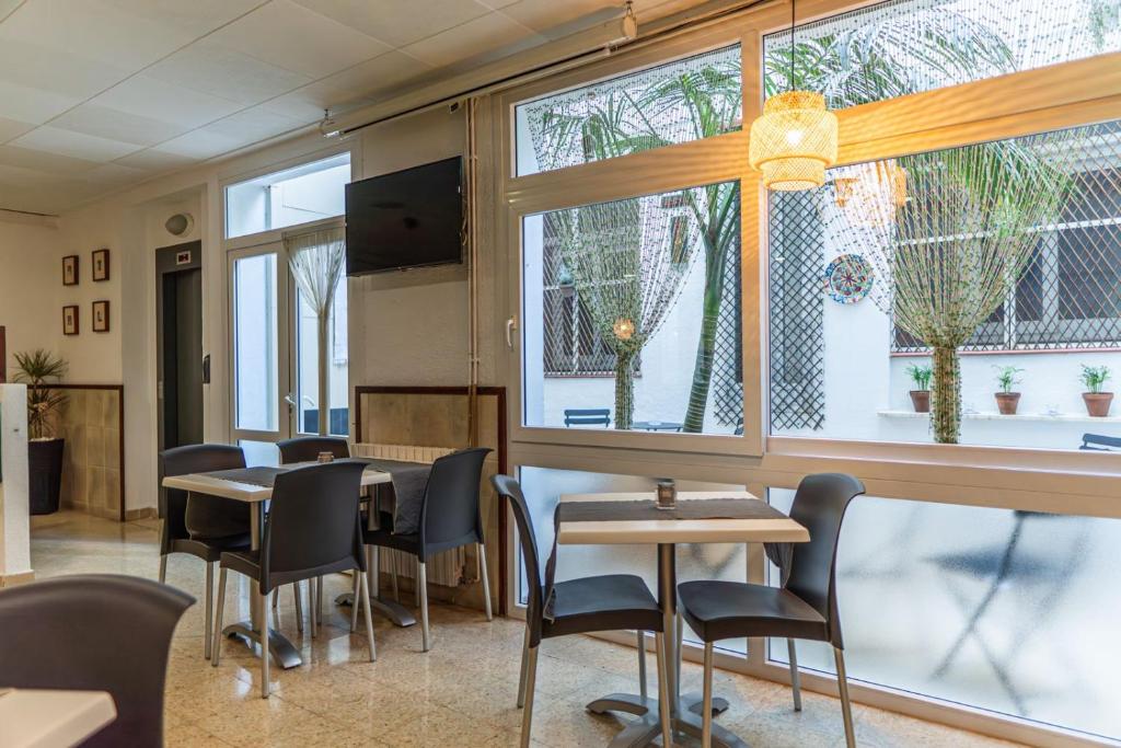 a dining room with tables and chairs and windows at Hostal Regina in Blanes