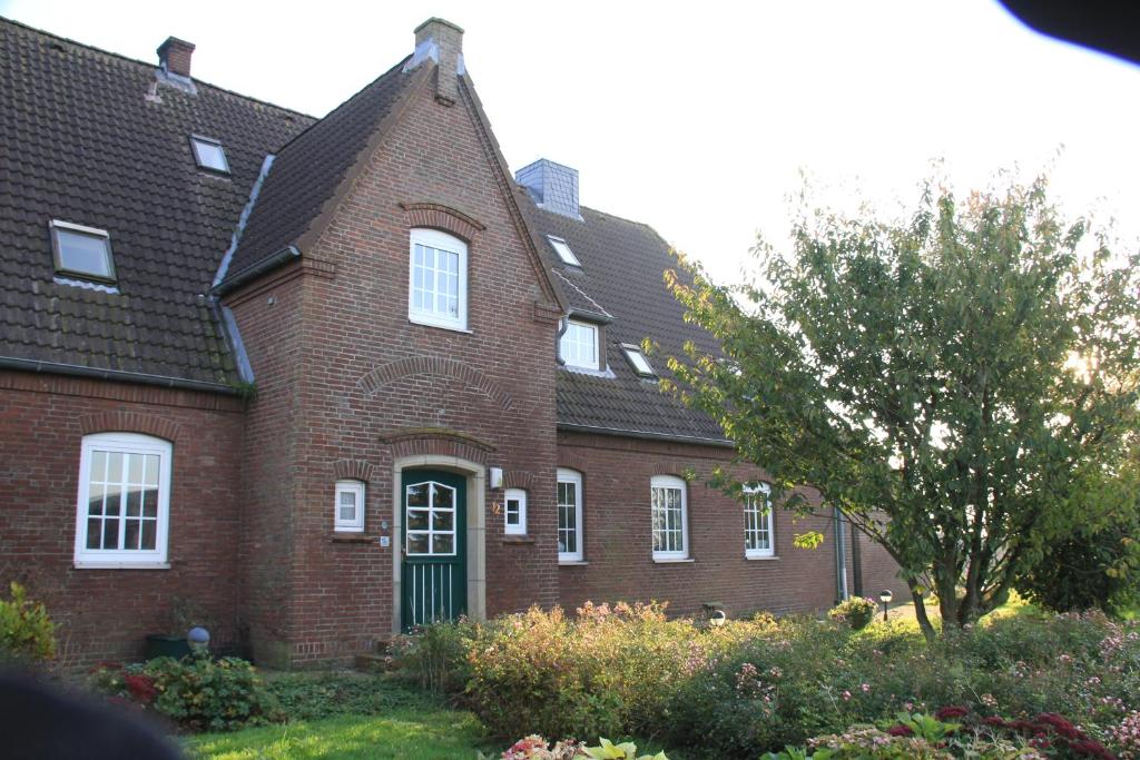 ein rotes Backsteinhaus mit grüner Tür in der Unterkunft Pension Nordwind in Hedwigenkoog