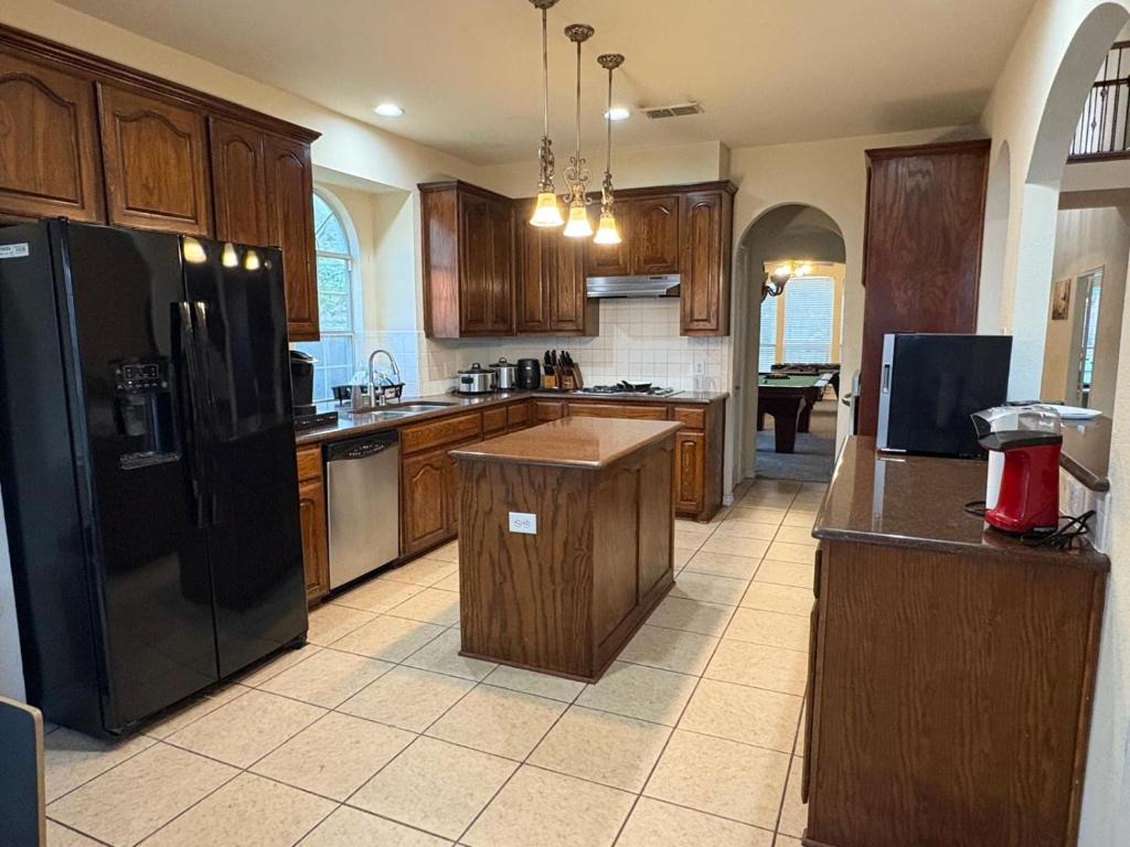Little ElmにあるSpacious 6 bedroom Home - Gym - Office - Games - Near PGA Frisco & Universal kidsの木製のキャビネットと黒い冷蔵庫を備えたキッチン