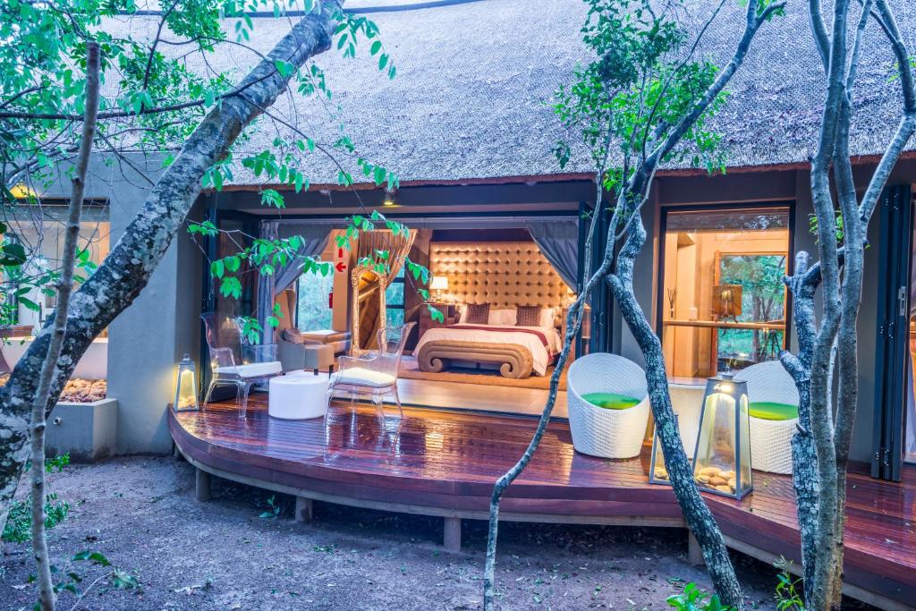 a house with a bed and chairs in a yard at AM Lodge - Hoedspruit in Hoedspruit