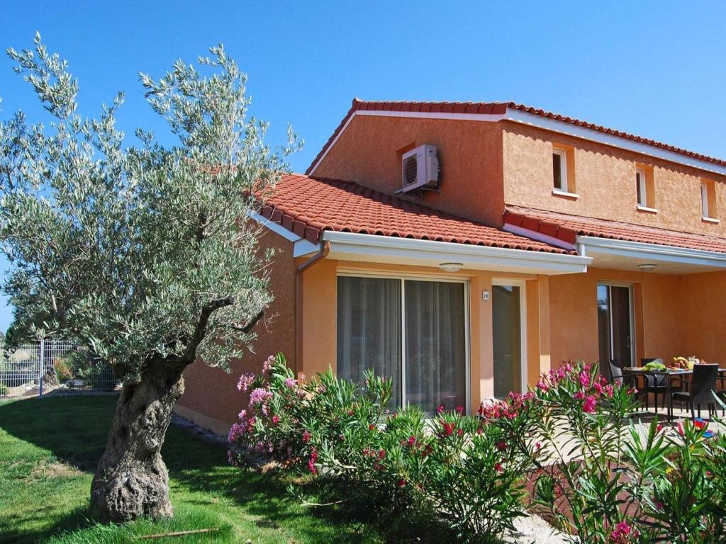 une maison avec un arbre dans la cour dans l'établissement Family-Friendly Coastal Retreat, à Torreilles