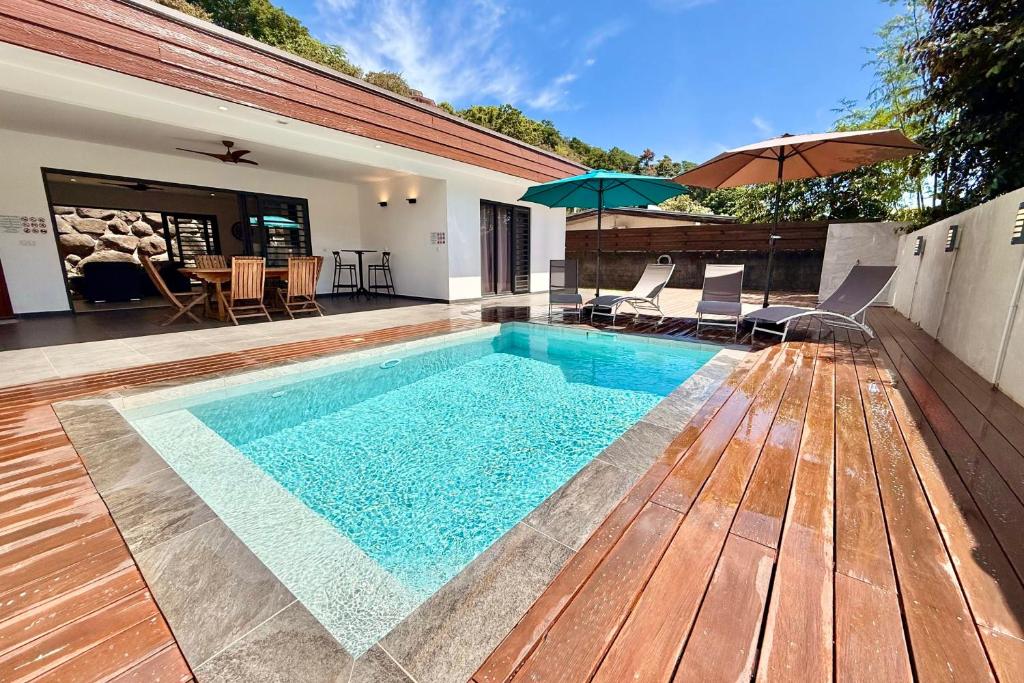 PiraeVilla Moea private pool confort & serenity in Pirae - AC- Wifi - 3 bdr的一个带遮阳伞的木甲板上的游泳池