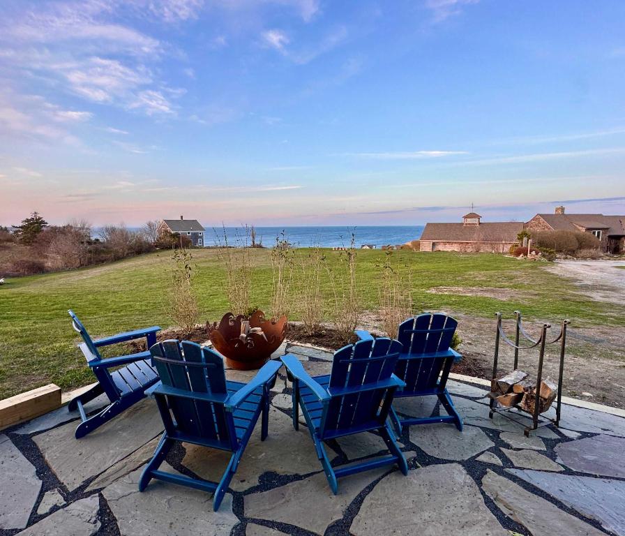 three blue chairs and a table with a view of the ocean at Harbor Point Haven in New Shoreham