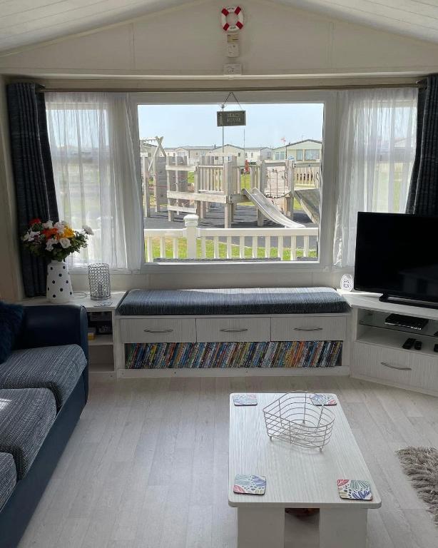 a living room with a couch and a large window at Willow Way 256 in Camber