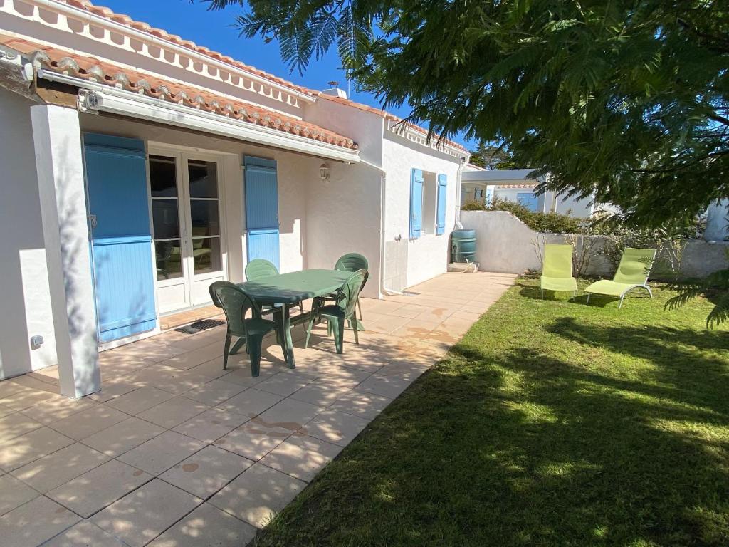 un patio avec une table et des chaises dans une cour dans l'établissement Maison mitoyenne à Barbâtre près de la plage - 4 personnes - FR-1-823-149, à Barbâtre