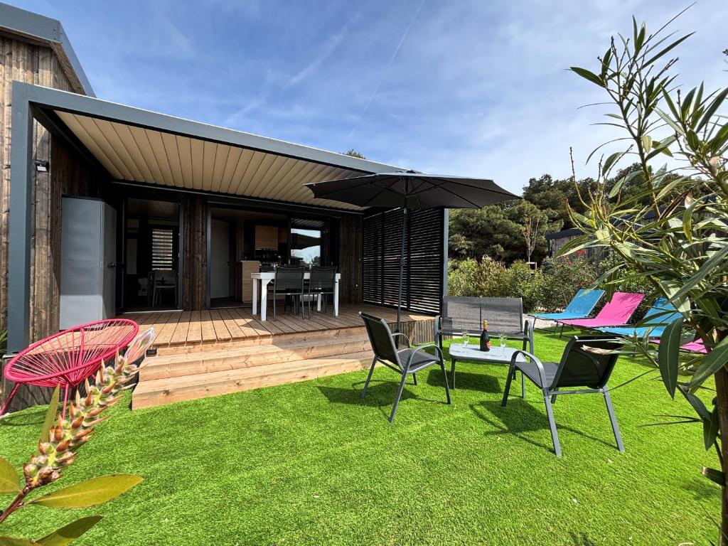une arrière-cour avec des chaises et une table avec un parasol dans l'établissement Chalet 2 chambres proche plages et Canal du Midi - FR-1-783-47, à Agde
