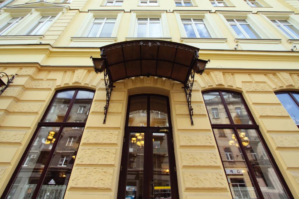 ein gelbes Gebäude mit Fenstern und Balkon in der Unterkunft Optima Dworzec Lviv in Lwiw