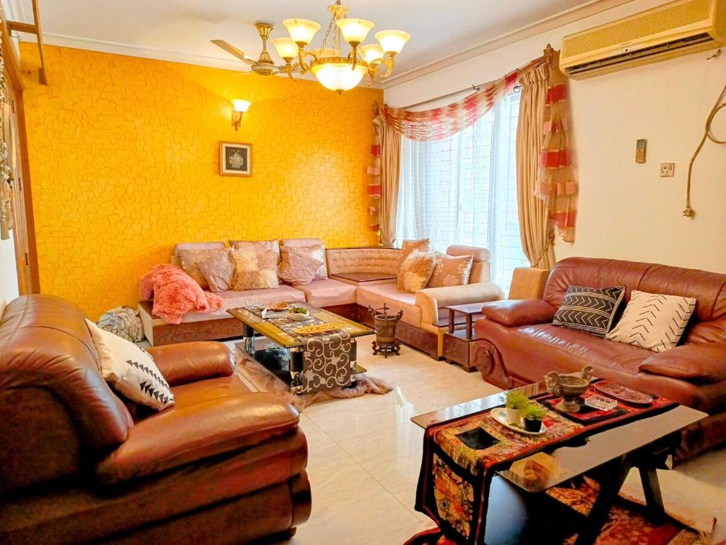 a living room with brown leather furniture and yellow walls at Luxury 3 bed apartment in Dhaka
